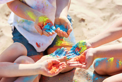 Low section of people sitting on sand with powder paint