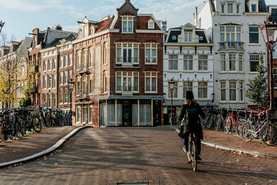 Man riding bicycle on street against buildings in city
