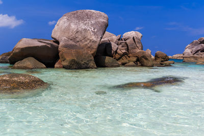 Rocks in sea against blue sky