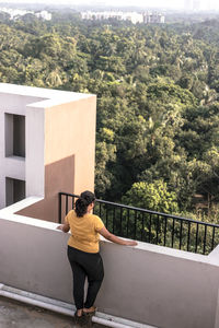 Rear view of woman standing by railing against trees