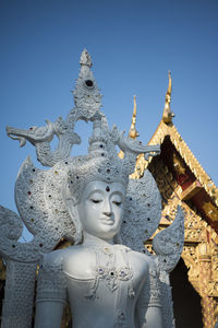 Buddha statue by temple against sky