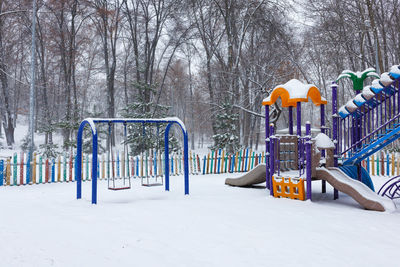 Snow covered playground in the city park on a winter day.