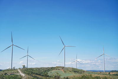 Wind turbines on field against clear blue sky