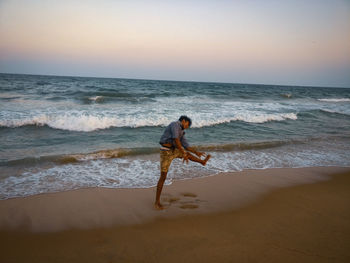Full length of woman on beach against sky during sunset