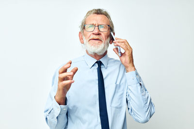 Senior businessman talking on phone against white background