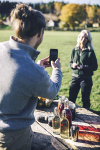 Mid adult man photographing female friend at farmer's market