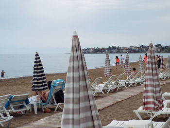 Lounge chairs and umbrellas at beach against sky