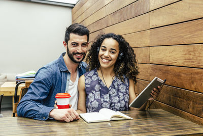 Portrait of smiling young couple sitting at cafe