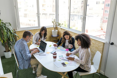 Male and female colleagues sitting at table while working in office