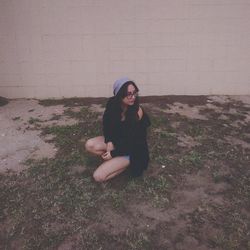 Woman crouching against wall during sunset