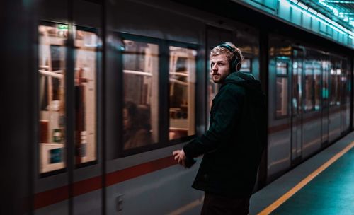 Thoughtful man standing against train at railroad station