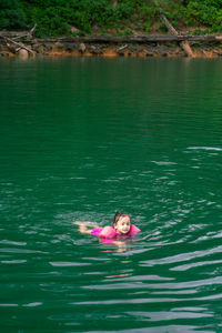 Portrait of cute little asian girl swimming, happy child having fun in water.