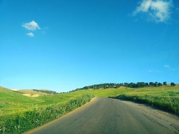 Road amidst field against sky