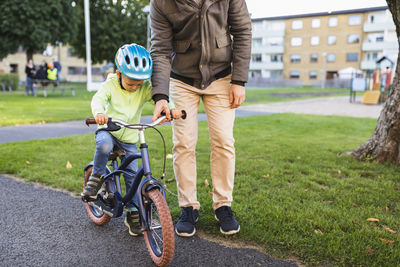 Father teaching son to ride bicycle on road