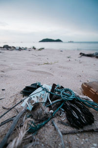 Close-up of rope on sand at beach against sky