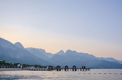 Group of people on beach by mountains against clear sky