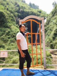 Side view of young man standing against wall