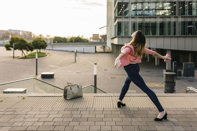 Rear view of woman walking on footpath in city