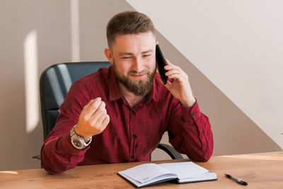 Focused bearded business guy in office clothes sitting at table and talking