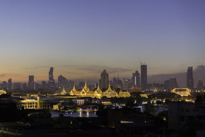 Illuminated cityscape against clear sky at night