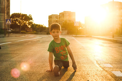 Portrait of boy stretching legs on road in city