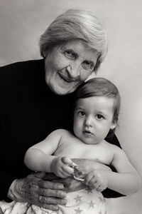 Old gray-haired grandmother sits with a small grandson in the studio