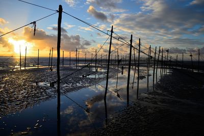 Salmon trap at beach against cloudy sky during sunrise