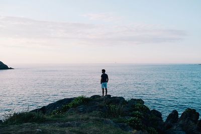 Rear view of man standing on beach against sky