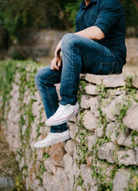 Side view of man sitting on rock