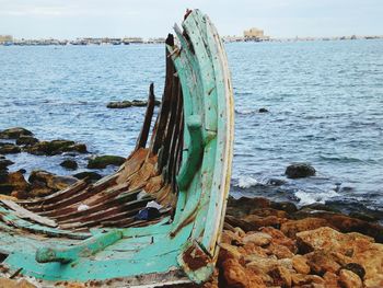 Abandoned boat on beach against sky