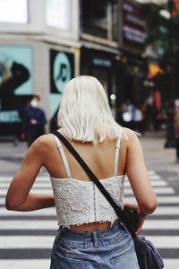 Rear view of woman standing on street in city