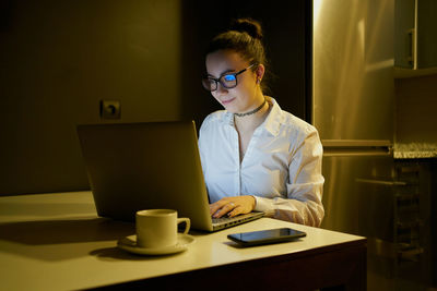 Young woman working with laptop in evening