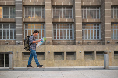 Full length side view of a man standing against building