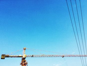 Low angle view of crane against clear blue sky