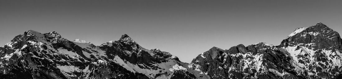 Low angle view of snowcapped mountains against clear sky