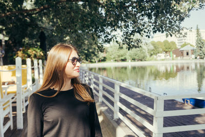 Portrait of beautiful young woman standing against plants