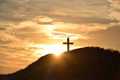 Low angle view of silhouette cross against dramatic sky