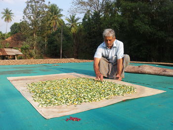 Full length of man putting vegetables for drying