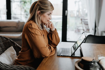 Side view of businesswoman talking on phone at home