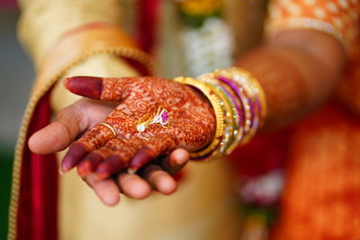 Close-up of couple holding engagement rings on palm of hands