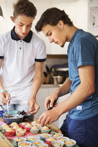 Young men making cupcakes