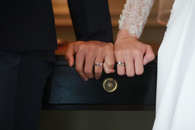 Cropped hands of newlywed couple showing wedding rings at table