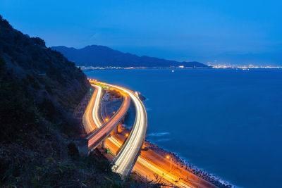 High angle view of light trails by sea against sky at night