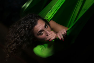 Portrait of beautiful woman lying on hammock in darkroom