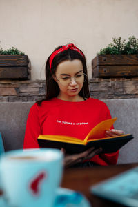 Young woman looking away while sitting on table