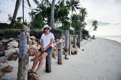 Woman sitting on palm tree by sea