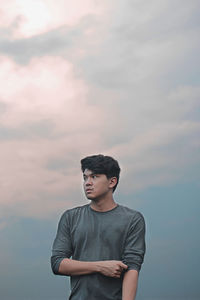 Young man standing against sky