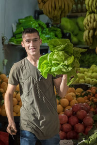 Portrait of young man carrying vegetables at market
