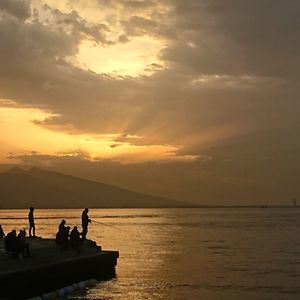 Silhouette people on sea against sky during sunset