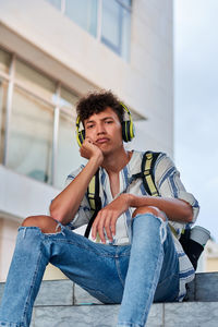 Boring young afro with headphones on sitting on the street